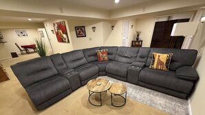 Una sala moderna con un sofá modular, dos mesitas redondas y cojines decorativos.