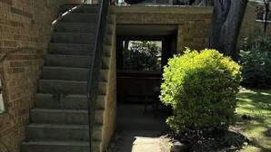 Un sendero de concreto que lleva a una escalera con barandilla metálica.