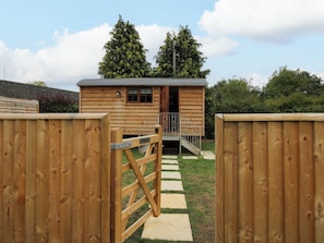 A wooden cabin with a metal gate, a staircase leading to a porch, and a clear sky. - Woodie (Ludlow)