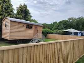 A wooden cabin with a metal roof, a small porch, and a staircase leading to the door.