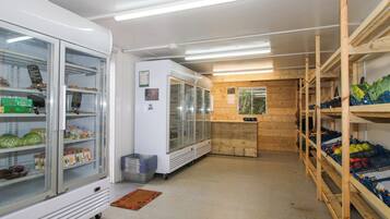 A grocery store interior with refrigerated display cases, wooden shelving, and a checkout counter.