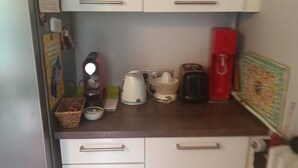 A compact kitchen with white cabinets, a coffee maker, a kettle, and a toaster. - 2-room apartment in a large, quiet house with garden and shared spaces (Vence)