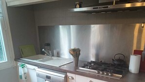 A kitchen with a dishwasher, stove, and a window. - 2-room apartment in a large, quiet house with garden and shared spaces (Vence)