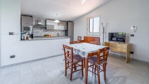Ett modernt kök med matplats, TV och skrivbord.