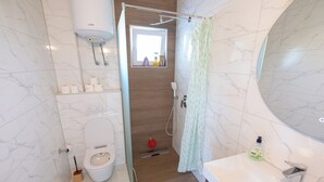 A modern bathroom with a toilet, shower, and sink.