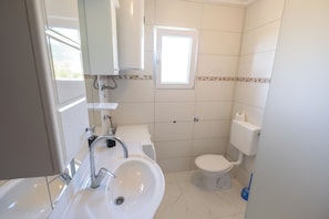A bathroom with a sink, toilet, and window.