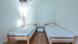 A room with two wooden beds, a nightstand, and a floor lamp.