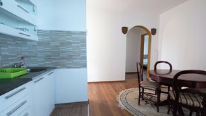 A modern kitchen with white cabinets, a green dish rack, and a wooden dining table with chairs.