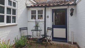 Een klein terras met een tafel, stoelen, een deur en een raam.