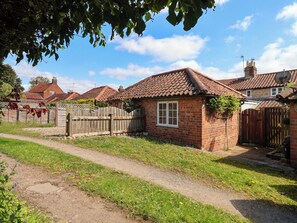 A brick house with a tiled roof, a wooden fence, and a path leading to the house. - The Cooks Cottage (Malton)