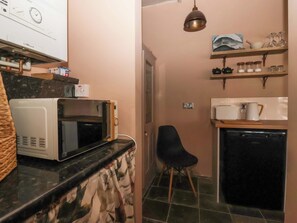 Pieni, käytännöllinen keittiö, jossa on mikroaaltouuni, musta tuoli ja astianpesukone.