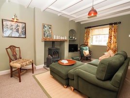 A cozy living room with a green sofa, a wooden chair, a fireplace, and a television.