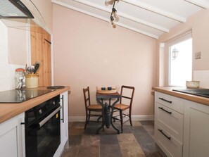 Una cocina con encimera de madera, estufa, mesa de comedor con sillas y ventana.