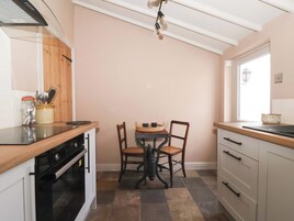 Una cocina con encimera de madera, estufa, mesa de comedor con sillas y ventana.