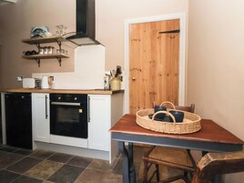 Cocina compacta con horno integrado, puerta de madera y mesa con cesta.