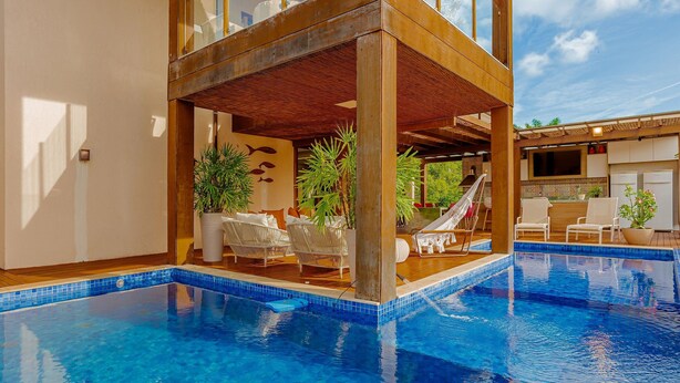 Ein moderner Poolbereich mit Holzterrasse, Liegestühlen und Topfpflanzen.