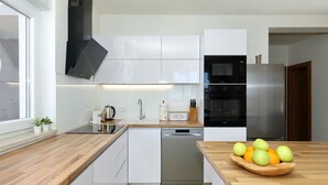 A modern kitchen with white cabinets, a stainless steel refrigerator, and a wooden countertop. - Apartment Temida with sea view (Rovanjska)
