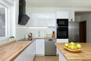 A modern kitchen with white cabinets, a stainless steel refrigerator, and a wooden countertop. - Apartment Temida with sea view (Rovanjska)