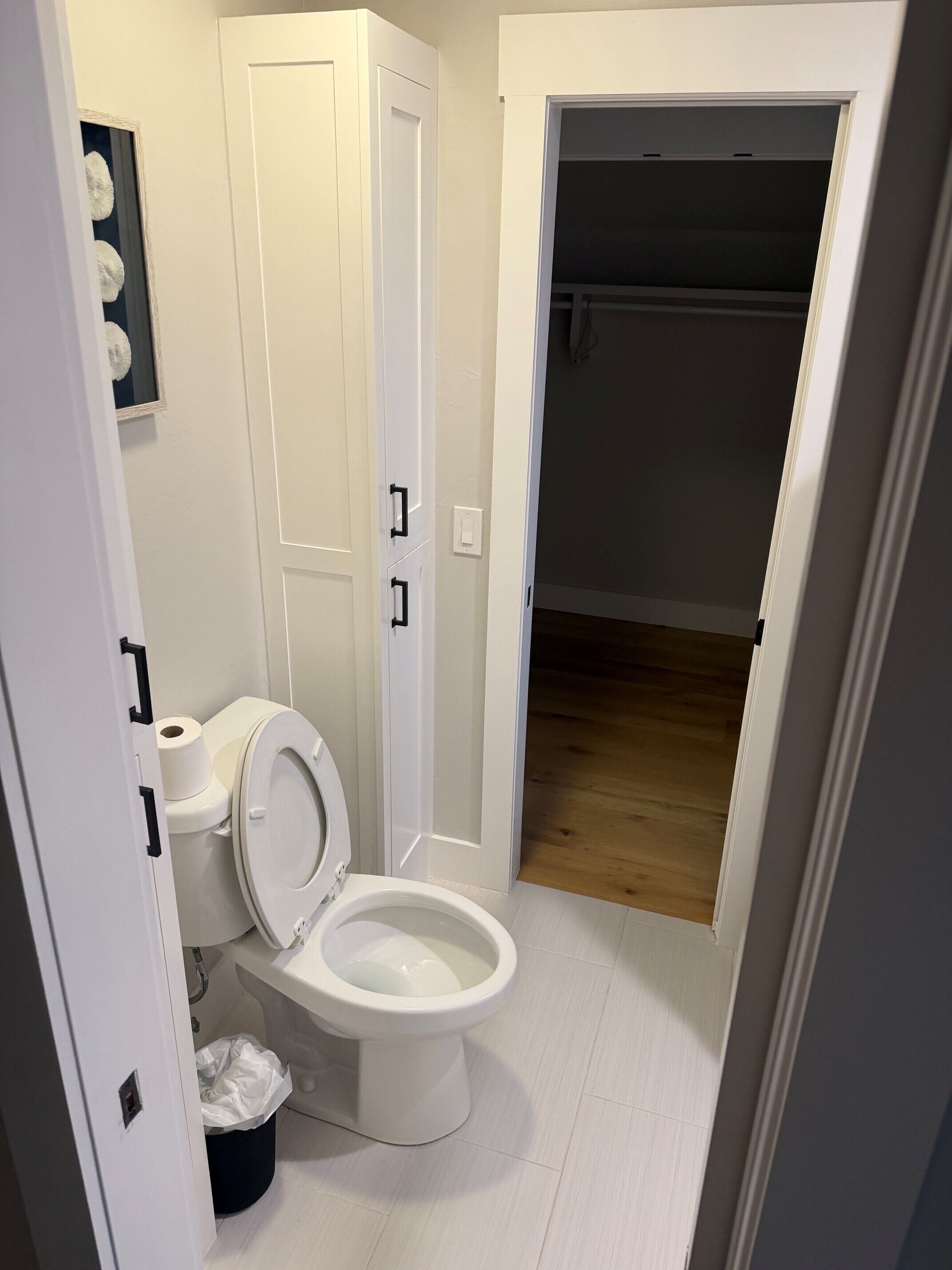Ein Badezimmer mit Toilette, Mülleimer und einer Tür zu einem Flur.