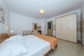 Ein Hotelzimmer mit Bett, Sessel, Schreibtisch, Kleiderschrank und Spiegel.