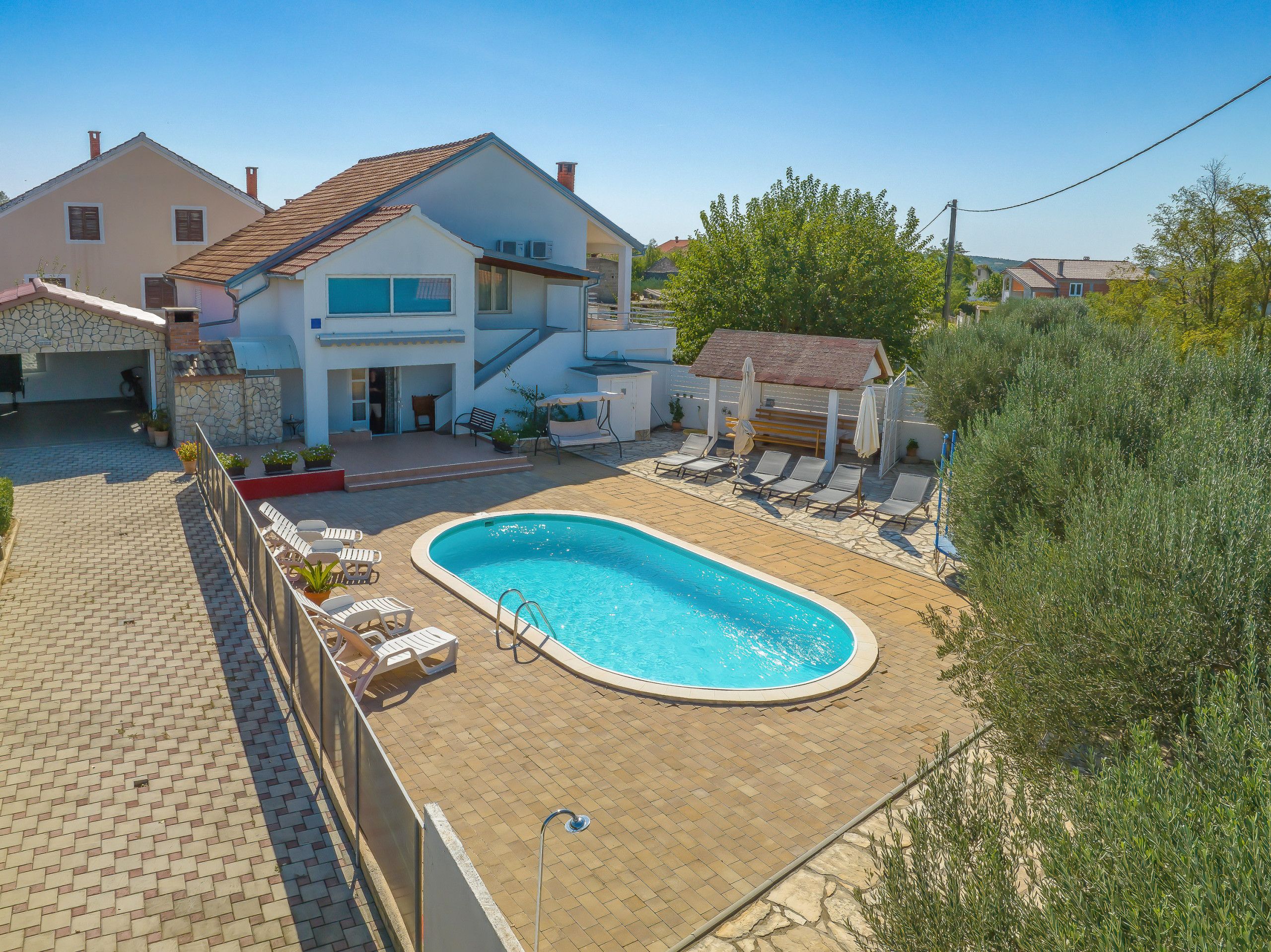 Une maison à deux étages avec une piscine, un espace salon extérieur et un jardin.