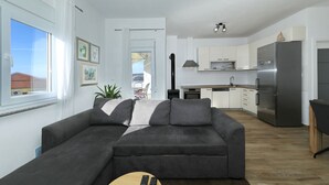 Una sala moderna con un sofá gris, una mesa de centro y vista a la cocina.