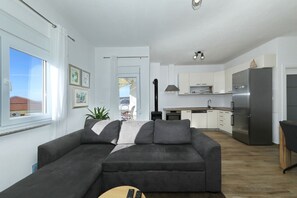 Ein modernes Wohnzimmer mit einem grauen Sofa, einem Couchtisch und Blick zur Küche.