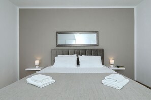 Ein Hotelzimmer mit einem Bett, zwei Nachttischen, einem Spiegel und gefalteten Handtüchern auf dem Bett.