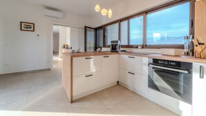 A modern kitchen with a built-in oven, a coffee maker, and a large window. - Holiday Home Pecora Nera with Pool (Ražanac)