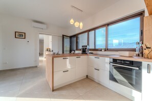 Eine moderne Küche mit Backofen, Kaffeemaschine und einem großen Fenster.