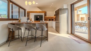 A modern kitchen with a bar area, large windows, and a view of the outside. - Holiday Home Pecora Nera with Pool (Ražanac)