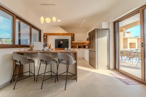 Eine moderne Küche mit Barbereich, großen Fenstern und Ausblick nach draußen.