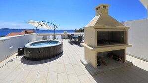 En takterrass med ett bubbelbad, utomhusmöbler och en vedeldad ugn.