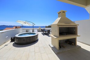 Eine Dachterrasse mit Whirlpool, Gartenmöbeln und einem Holzofen.