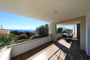 Ein Balkon mit Meer- und Stadtblick, ein Essbereich mit Stühlen und Tisch sowie ein Holzboden.