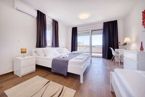 Ein modernes Hotelzimmer mit Bett, Nachttischen, einem Schreibtisch und Blick auf die Stadt.