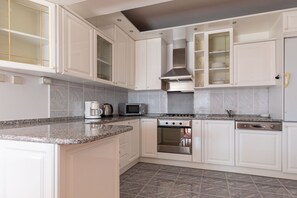 Eine moderne Küche mit weißen Schränken, einem eingebauten Backofen, einer Mikrowelle und einer Kaffeemaschine.