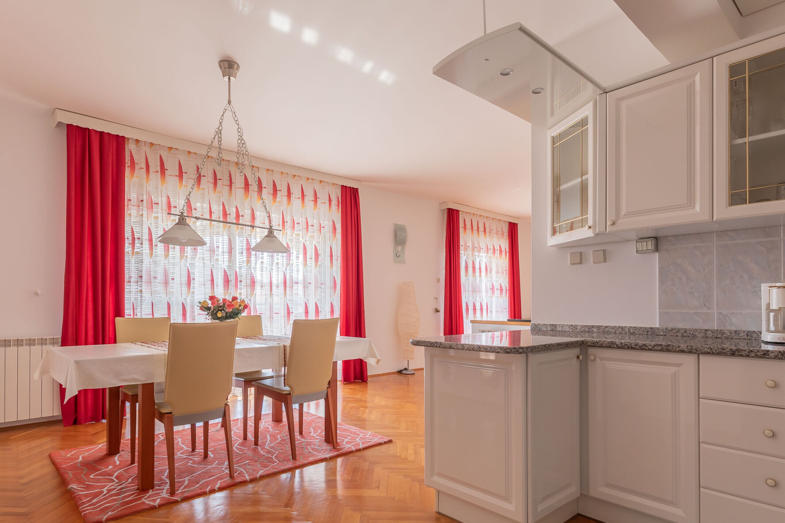 Een moderne keuken met witte kasten, een granieten aanrechtblad en een eethoek met een tafel en stoelen.