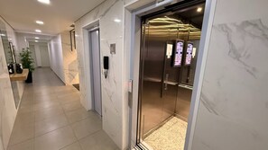 Ein moderner Flur mit Marmorboden, einer Tür zum Aufzug und einer Zimmerpflanze.