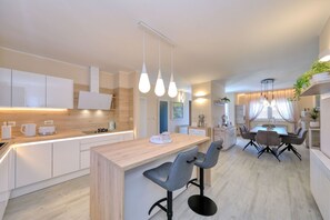 Eine moderne Küche mit einer Holztheke, Pendelleuchten und einem Essbereich mit Tisch und Stühlen.