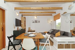 Ein Essbereich mit Holztisch und -stühlen, einer Couch und einem Fernseher.