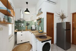 Eine kleine Küche mit Waschmaschine, Kühlschrank und Holzböden.