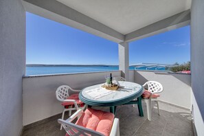 Ein Balkon mit Tisch und Stühlen, Blick aufs Meer und ein klarer Himmel.