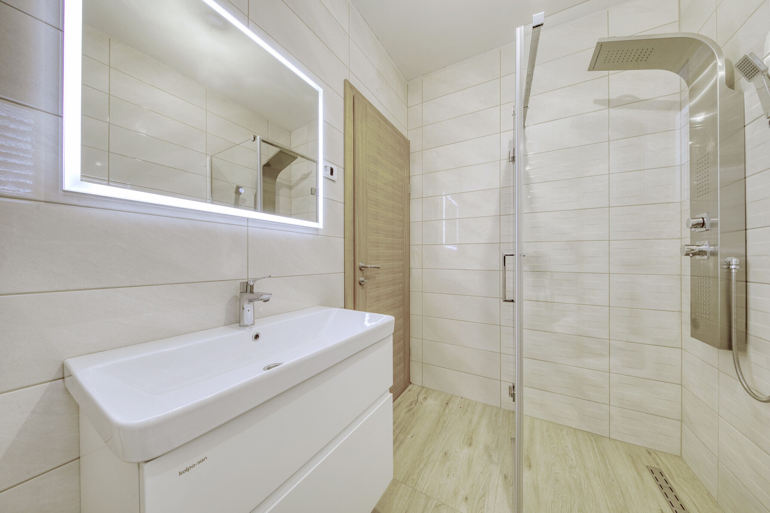 Une salle de bain moderne avec un lavabo blanc, un miroir et une douche.