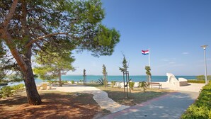 A coastal walkway with a flag, benches, and a view of the sea. - Apartment Perinic No.1 in Vrsi (Vrsi)