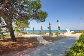 Ein Küstenweg mit einer Flagge, Bänken und Blick aufs Meer.