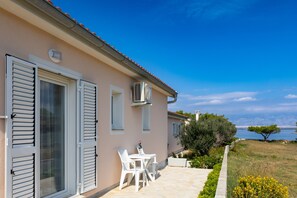 A house with a patio, white shutters, and a table with chairs. - Holiday Home Ana Maria by the Beach (Vir)