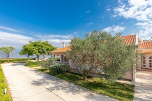 A residential property with a paved driveway, a large tree, and a building with a red-tiled roof. - Holiday Home Manuela with Private Beach Access (Vir)
