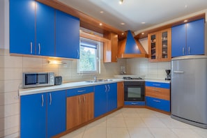 A modern kitchen with blue cabinets, a microwave, stove, sink, and refrigerator. - Holiday Home Manuela with Private Beach Access (Vir)