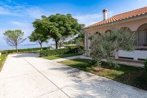 A pathway leading to a building with a tiled roof, surrounded by greenery and a clear sky. - Holiday Home Maria with Private Beach Access (Vir)
